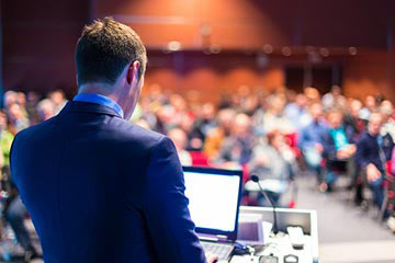 Man on laptop presenting on a podium