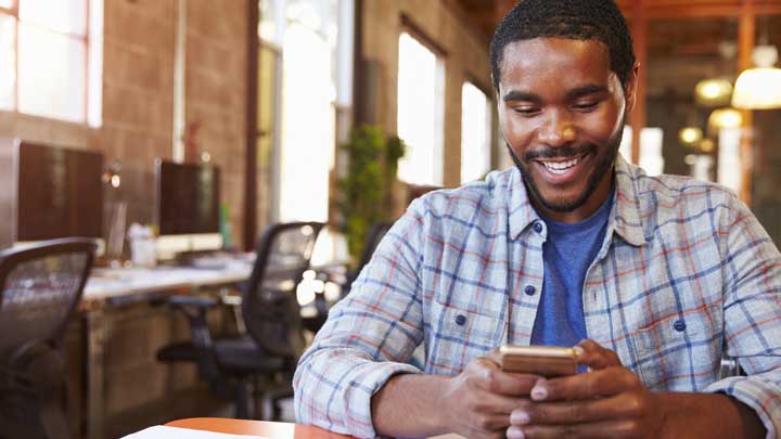 Man die zijn telefoon gebruikt glimlacht