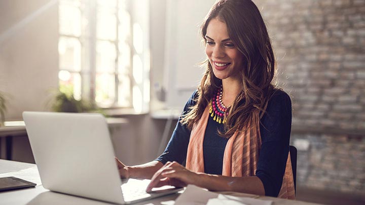 Mujer sonriente sentada trabajando en su laptop