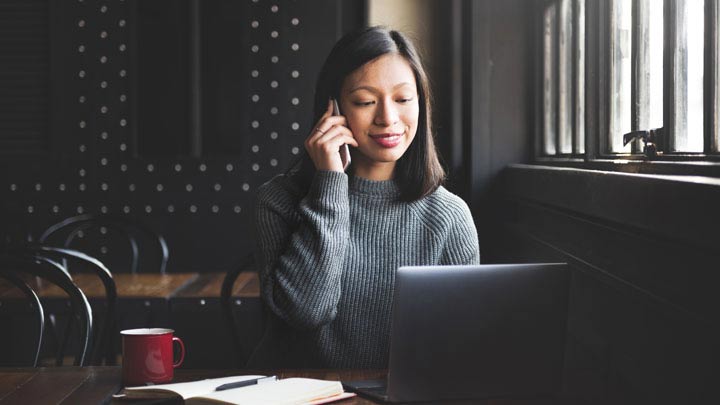 Woman on the phone sitting down with her laptop