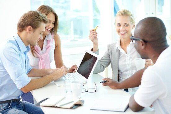 A group of co-workers huddled around a large computer screen